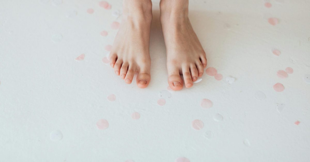 pexels-photo-6202204-6202204 Bare feet standing on a white background covered in soft pink petals.